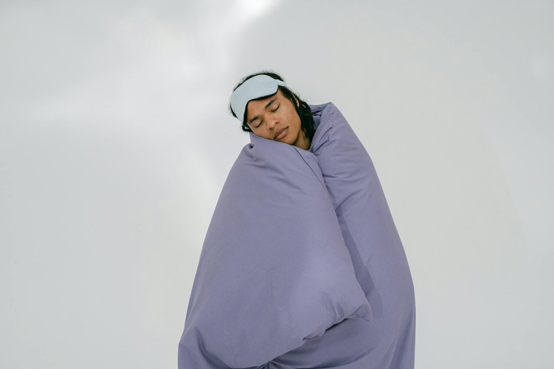 a man sleeping while covering his body with purple comforter