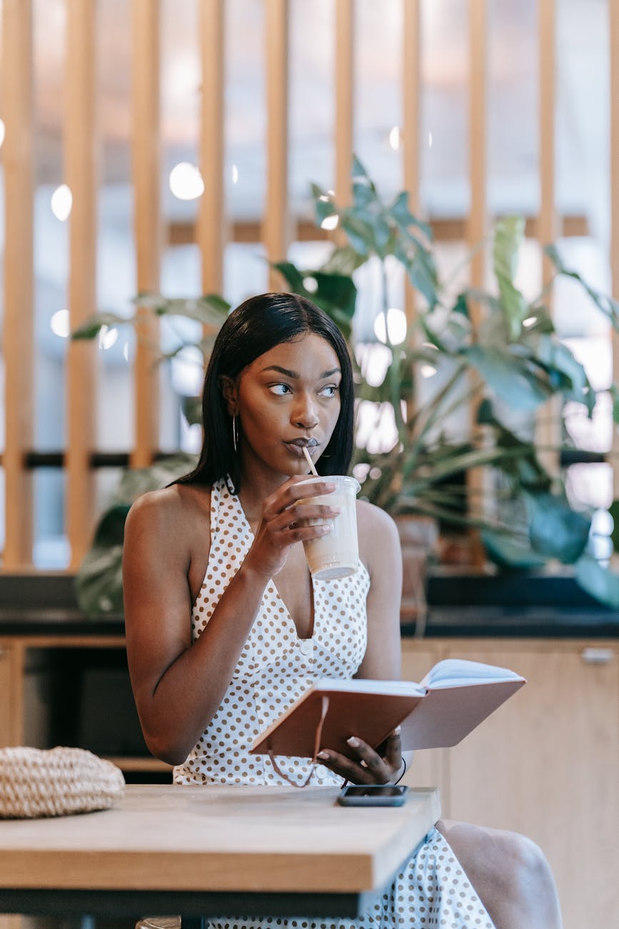 a woman drinking while holding a notebook
