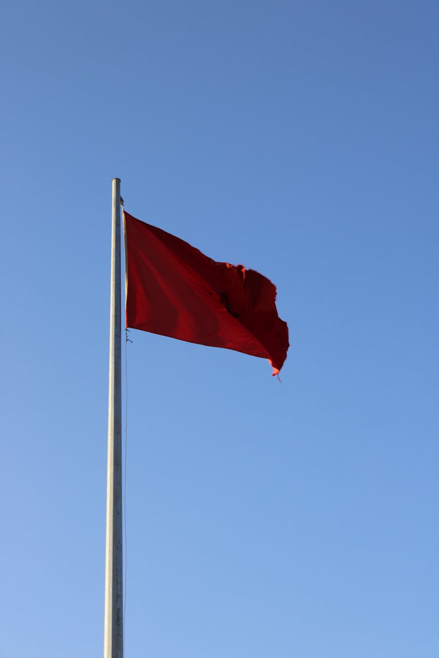 red flag waving against clear blue sky