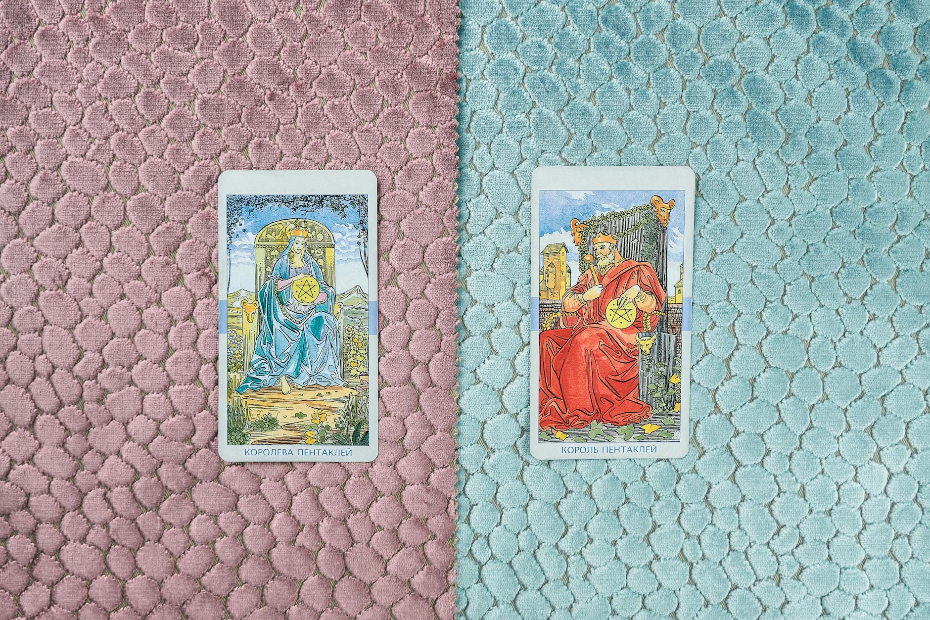 king and queen of pentacles cards on pink and blue fabric