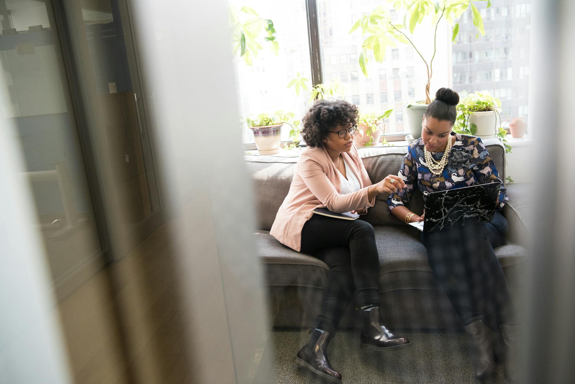 shallow focus photography of two woman sitting on gray couch