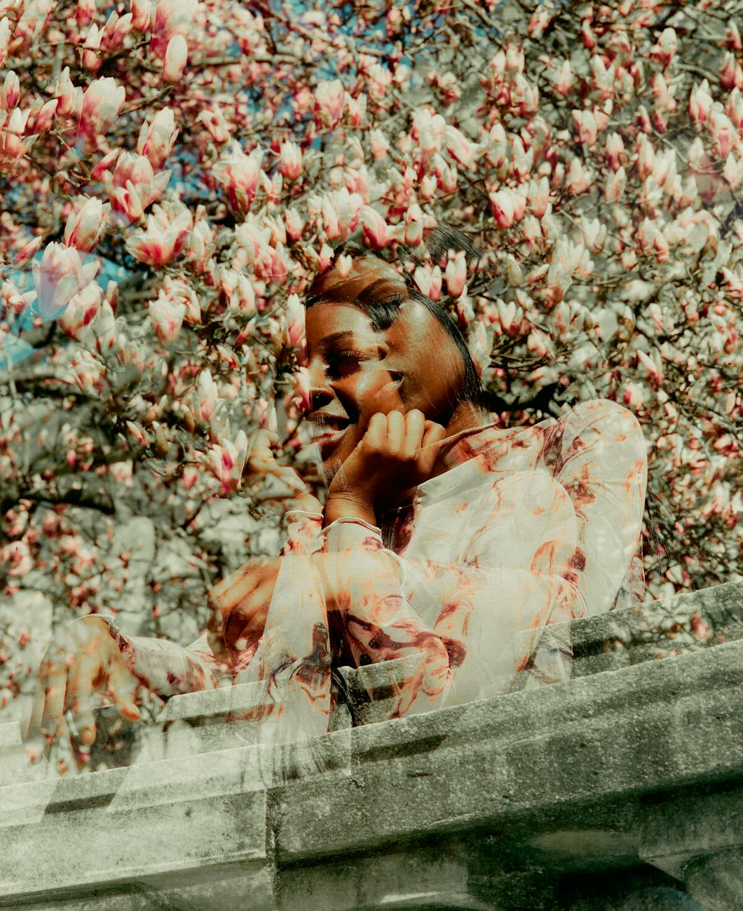 a woman is sitting on a bench in front of a tree