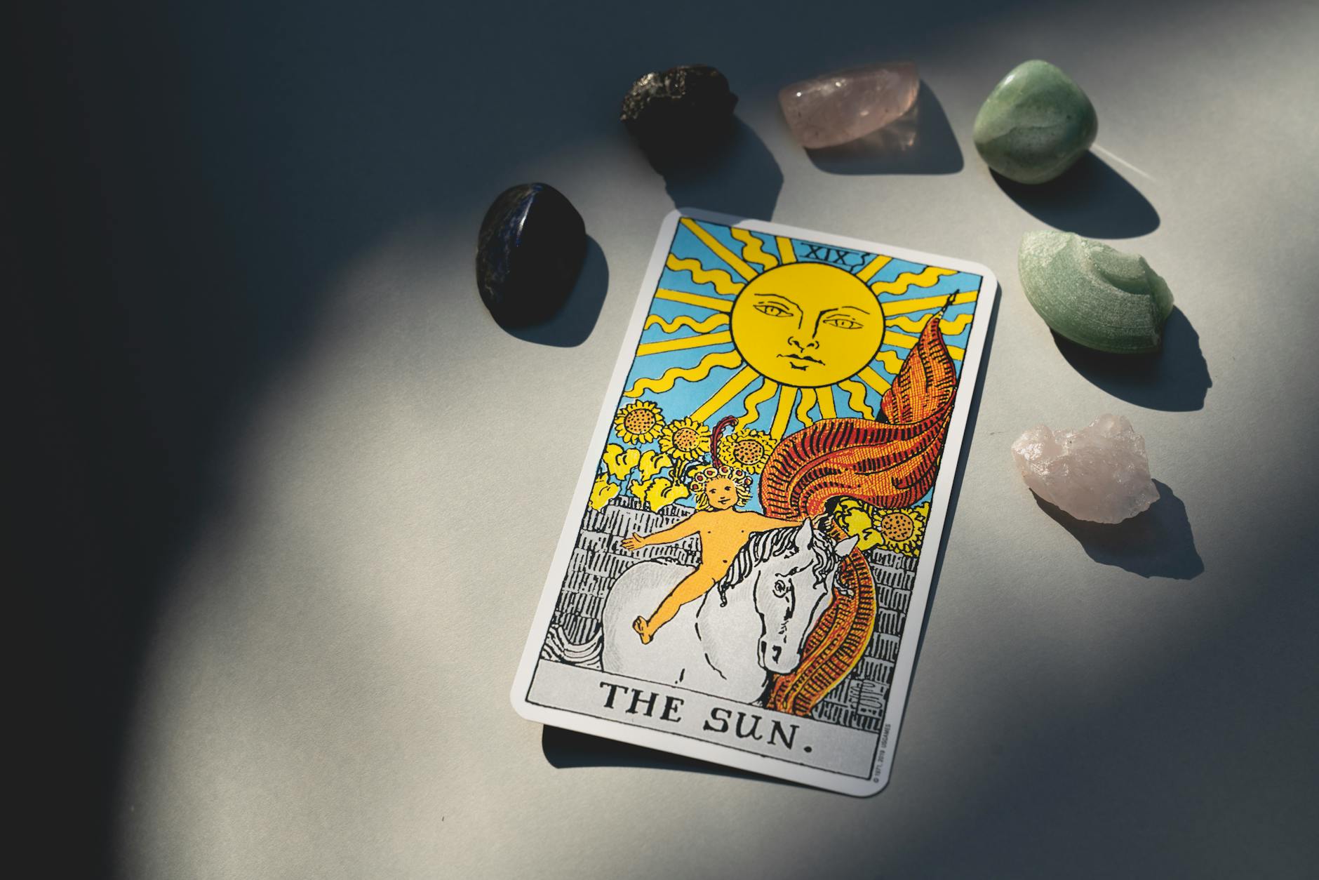 overhead shot of a tarot card and healing crystals