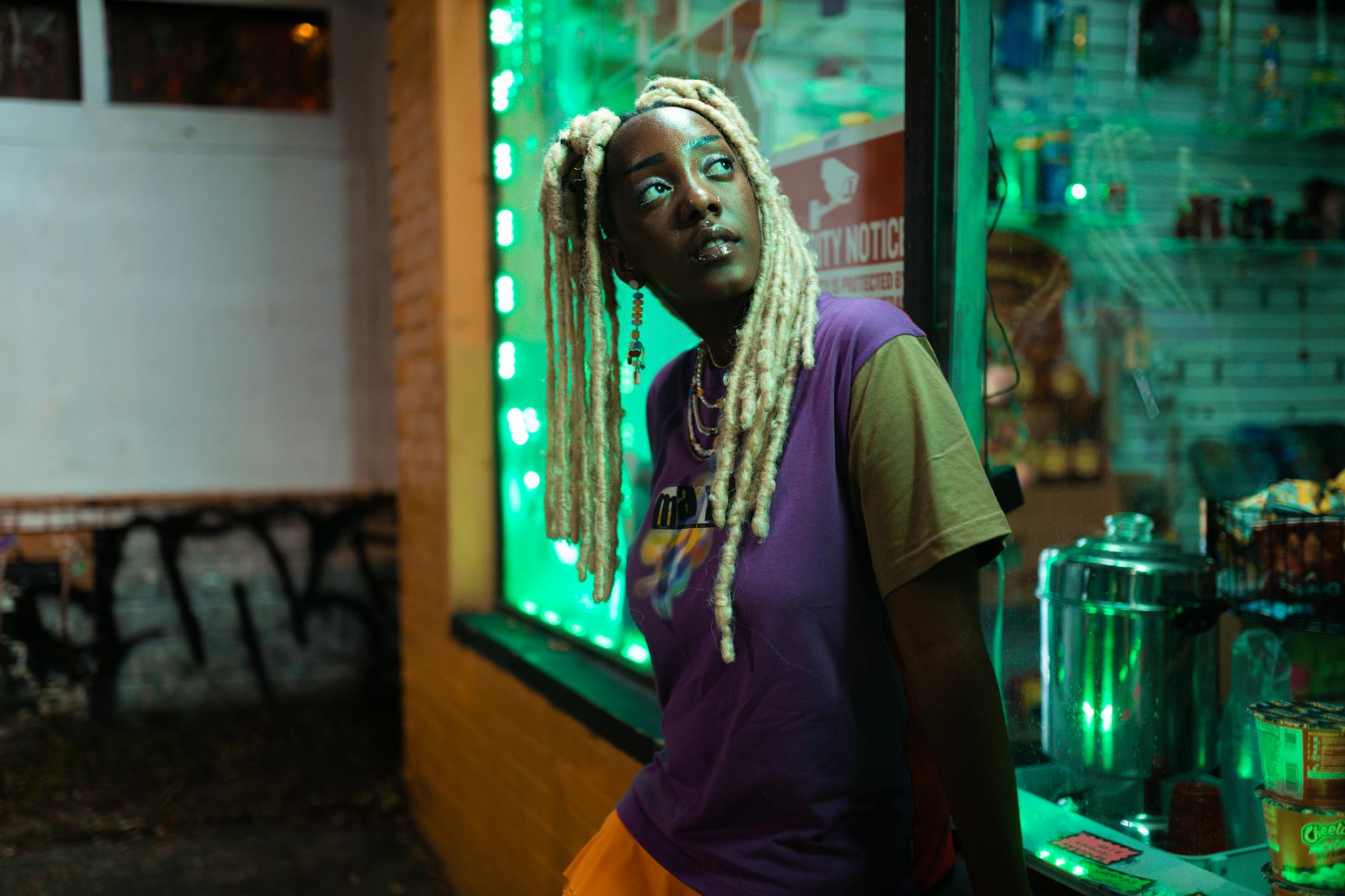black girl with blonde locs standing outside a store at night