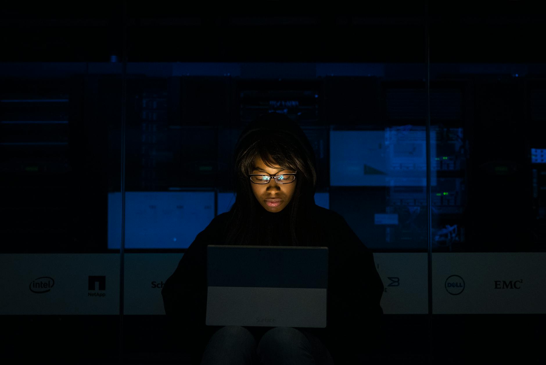woman wearing black hoodie jacket holding grey laptop computer